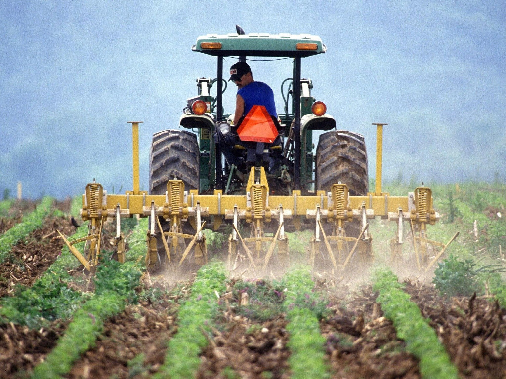 Tractor spreading pesticides on crops